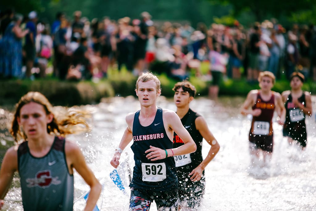 Cross country runner in water, racing others