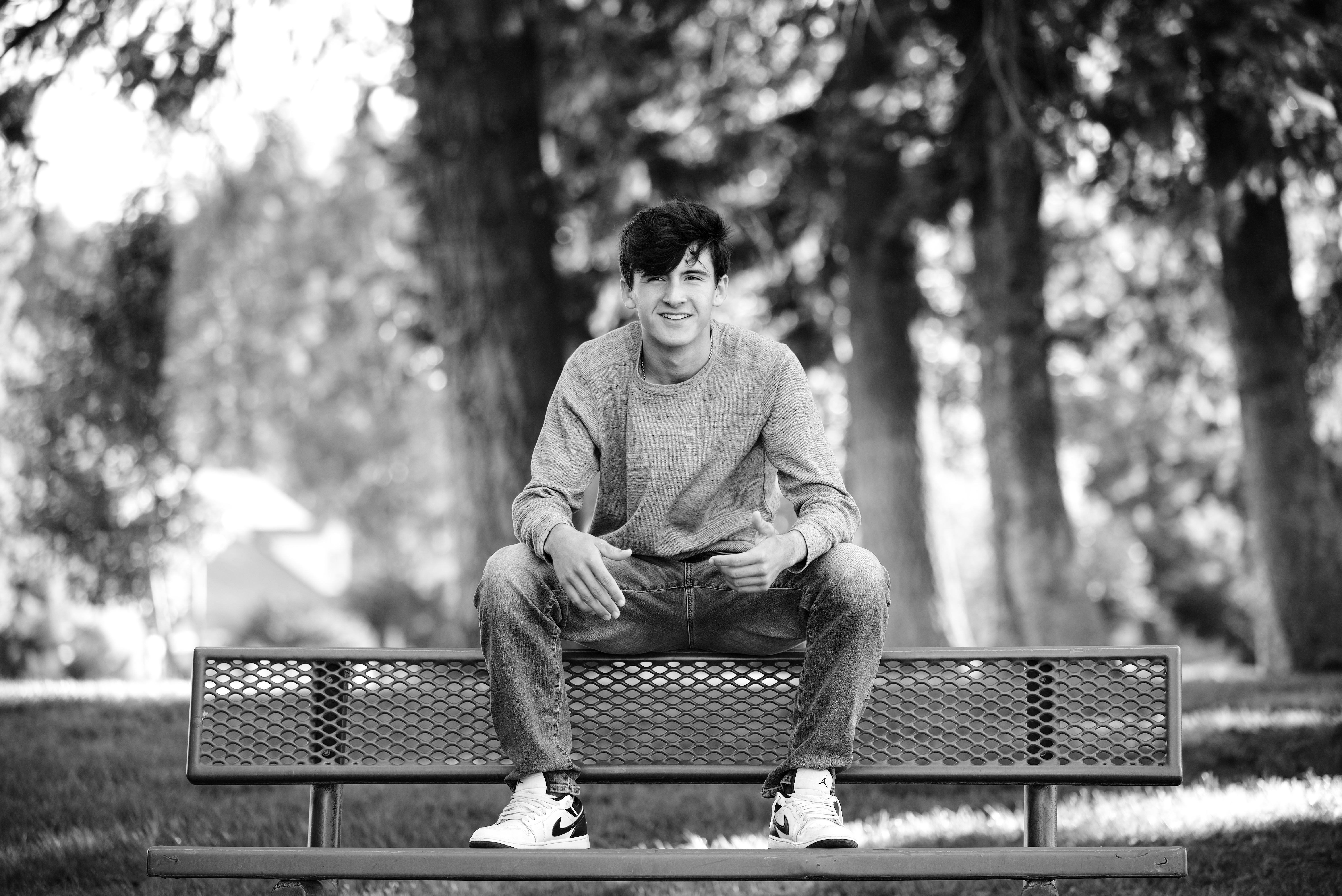 BW Photo of Senior boy sitting on bench in.a park